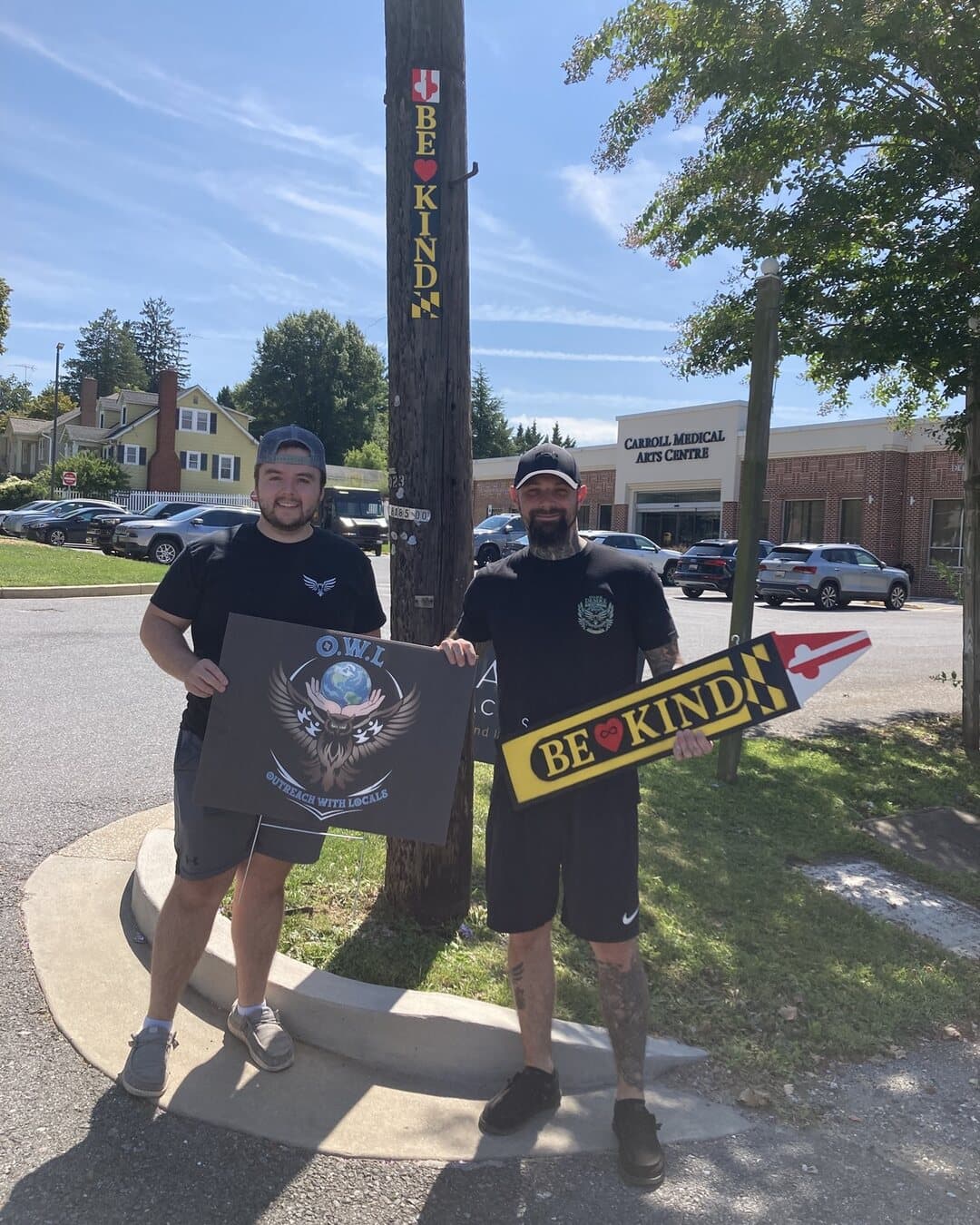Two neighbors holding our sign and a Be Kind sign