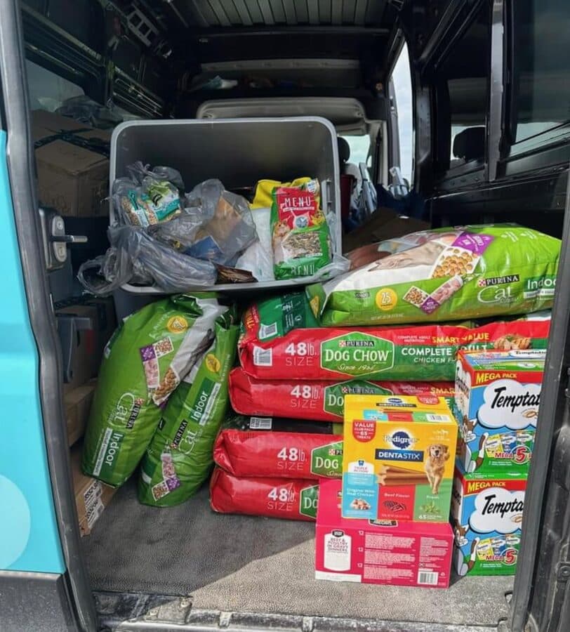 The back of a van loaded with bags of dog food and treats