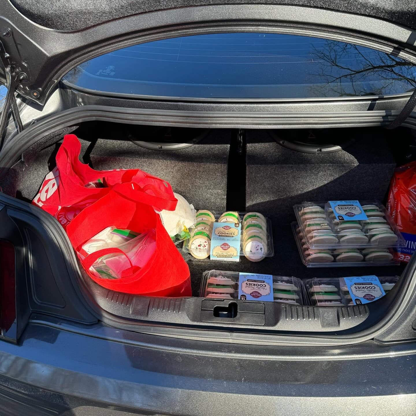 A car trunk loaded with red bags and packs of cookies